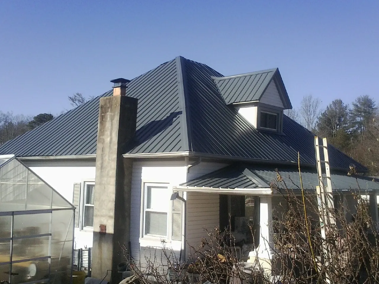 Dark blue standing seam metal roof on a white farmhouse with dormer — Slate & Tile Roof Repair by Roofing Brothers in Earleville