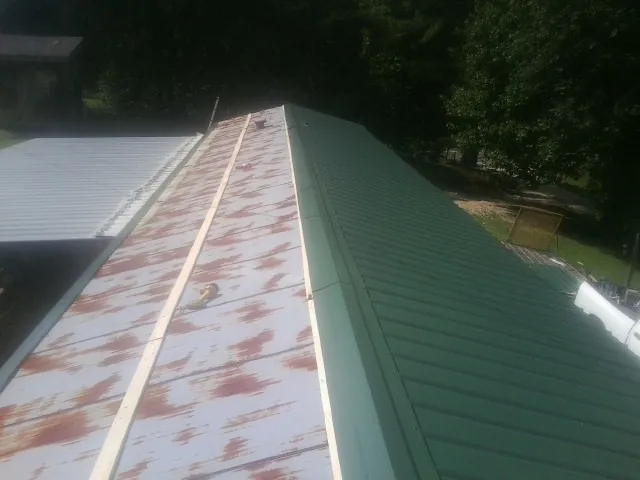 Old rusted panels beside newly installed green metal roofing — Wind Damage Roof Repair by Roofing Brothers in Earleville