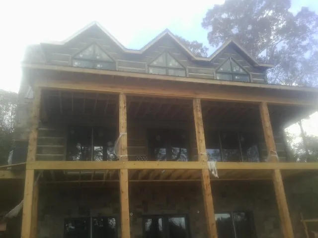 Dormers and porch framing on a large log home under construction — Roof Coating work by our crew in Earleville