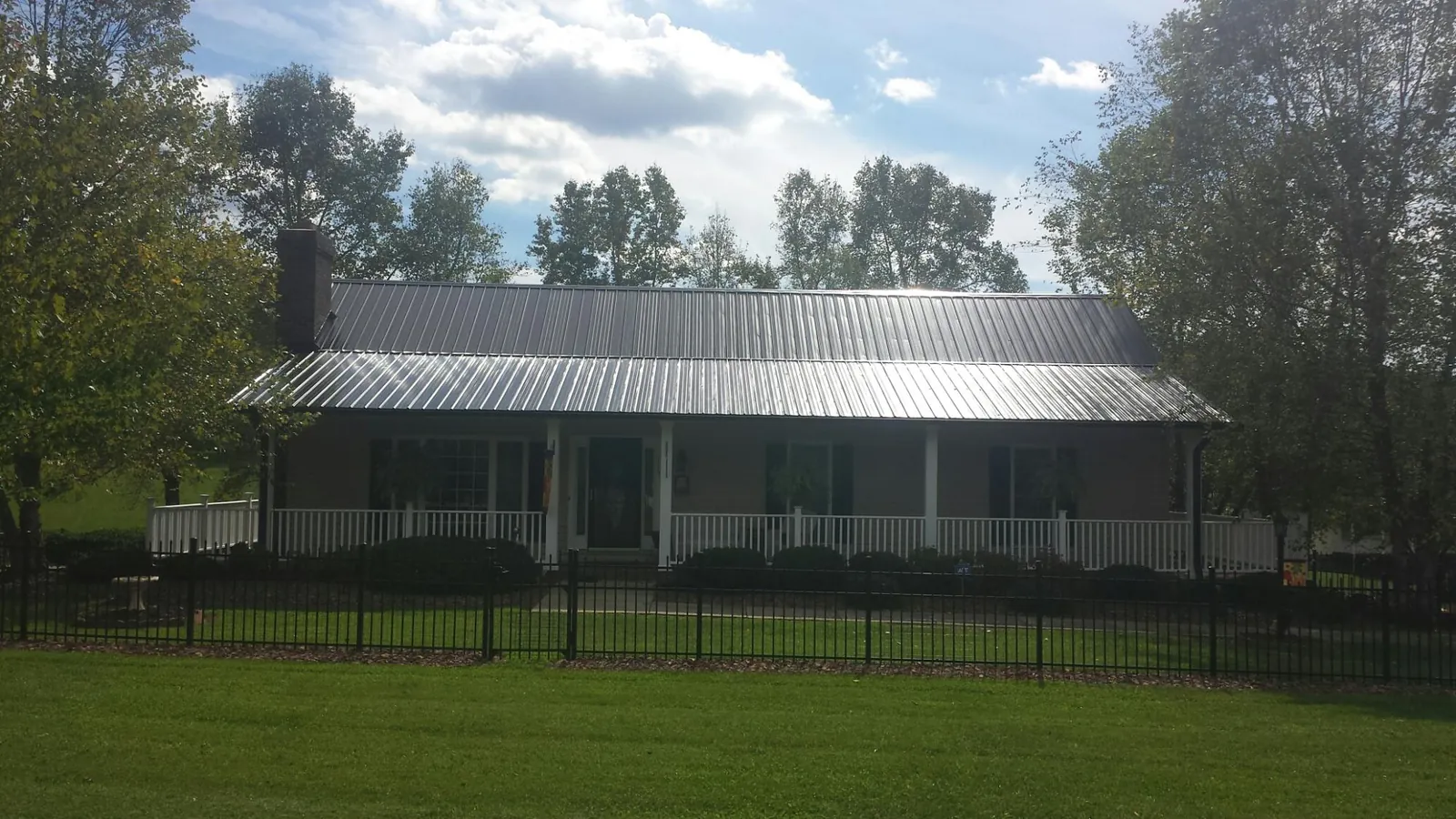 Gray metal roof on a brick ranch with a full width front porch — Gutter Guard Installation work by our crew in Earleville