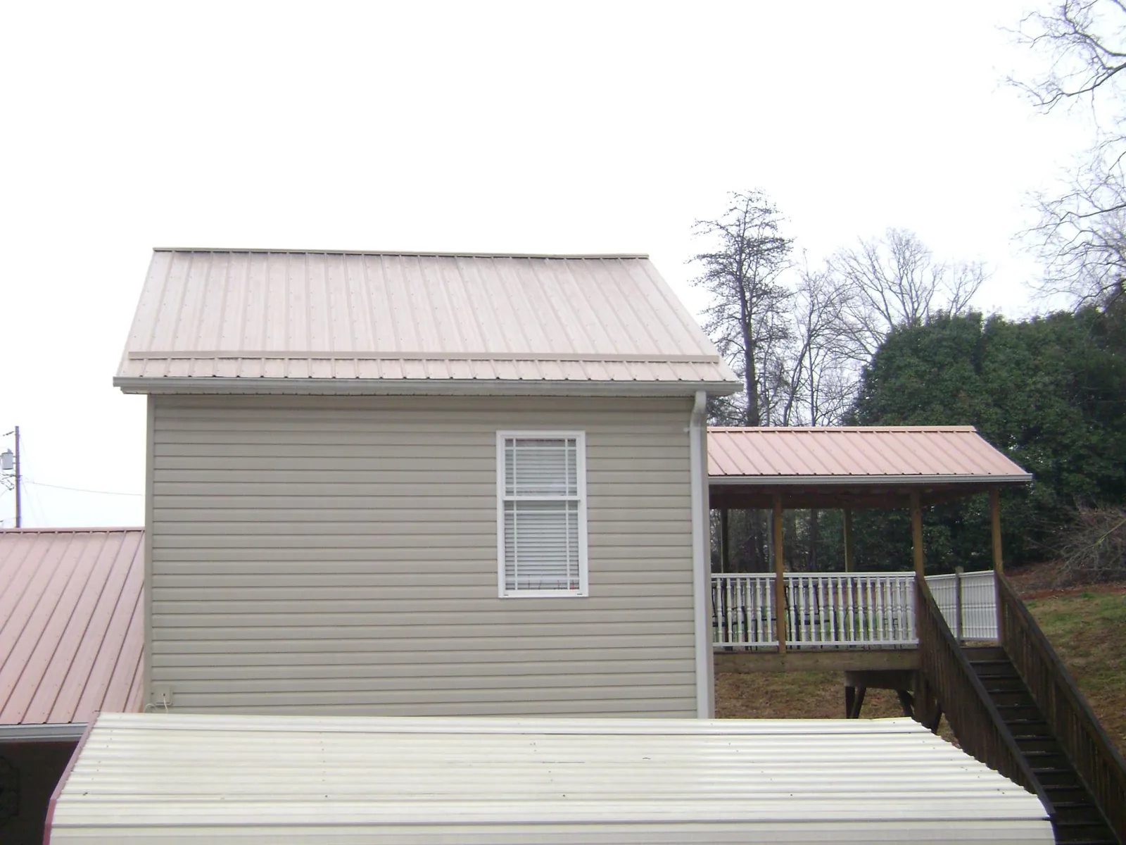 Tan metal roofs on a two story addition and attached porch, from a Roof Replacement job in Earleville