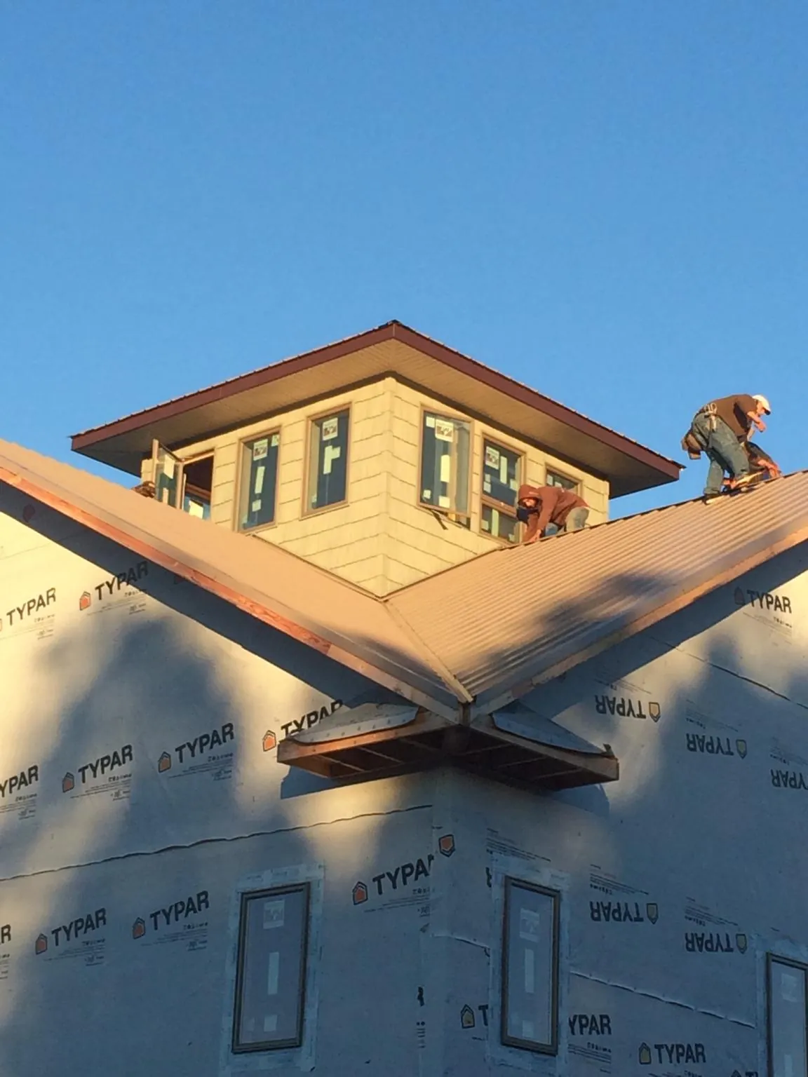 Roofers working around a rooftop cupola on a new metal roof at sunset — Roof Waterproofing in Earleville by Roofing Brothers